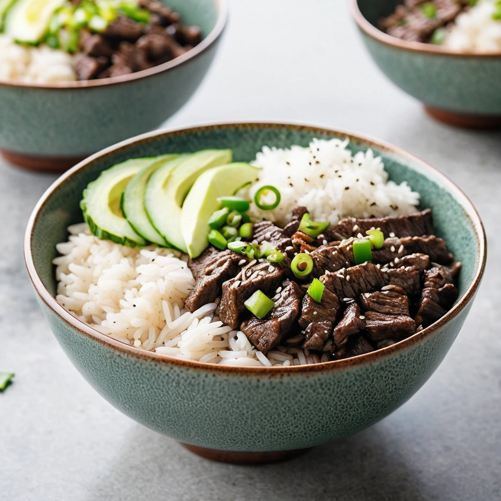 A bowl of white rice topped with caramelized beef strips, green onions, and sesame seeds.